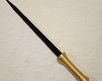 May include: A black metal sword with a gold-colored handle. The handle has a twisted design.