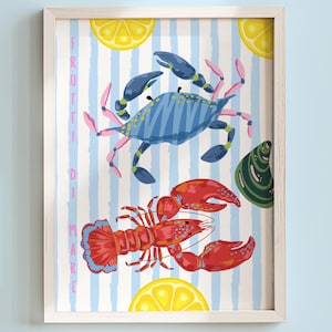 Op de afbeelding: Een ingelijste print met een blauwe krab en een rode kreeft op een gestreepte achtergrond. Het kunstwerk bevat citroenpartjes en een groene schelp, met de Italiaanse tekst "FRUTTI DI MARE".