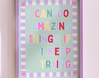 May include: A framed print with the text "I CAN DO AMAZING THINGS IF I KEEP TRYING." The text is in colourful block letters on a light green background with a striped border and purple frame. Small pink hearts are in the corners.