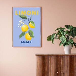 May include: A framed art print featuring a botanical illustration of lemons on a branch with green leaves and white flowers. The word "LIMONI" is printed in yellow at the top, and "AMALFI" is printed in blue at the bottom, all against a light blue background.