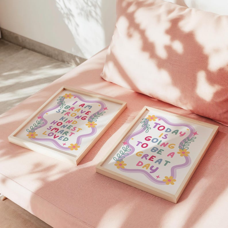 May include: Two framed art prints with inspirational quotes. One print reads "I AM BRAVE STRONG KIND HONEST SMART LOVED" in colorful text. The other says "TODAY IS GOING TO BE A GREAT DAY". Both are in light wood frames.
