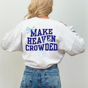 May include: A gray sweatshirt with the text "MAKE HEAVEN CROWDED" in navy blue letters. The text is surrounded by blue bows.
