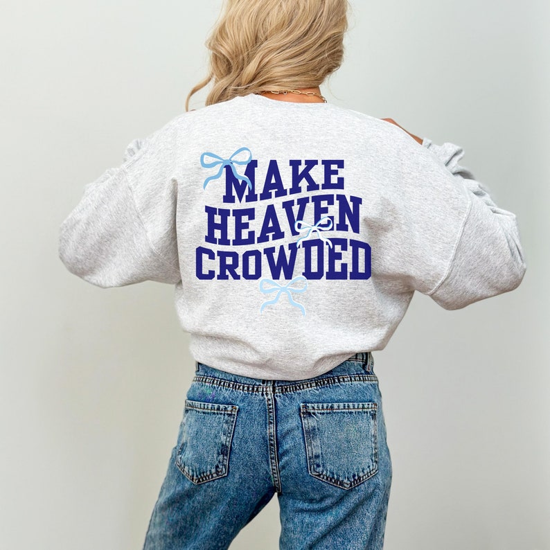 May include: A gray sweatshirt with the text "MAKE HEAVEN CROWDED" in navy blue letters. The text is surrounded by blue bows.