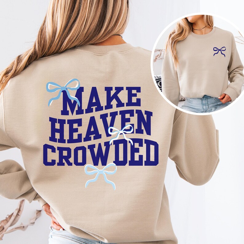 May include: A beige sweatshirt with the text "MAKE HEAVEN CROWDED" in navy blue letters. There are four blue bows on the sweatshirt.