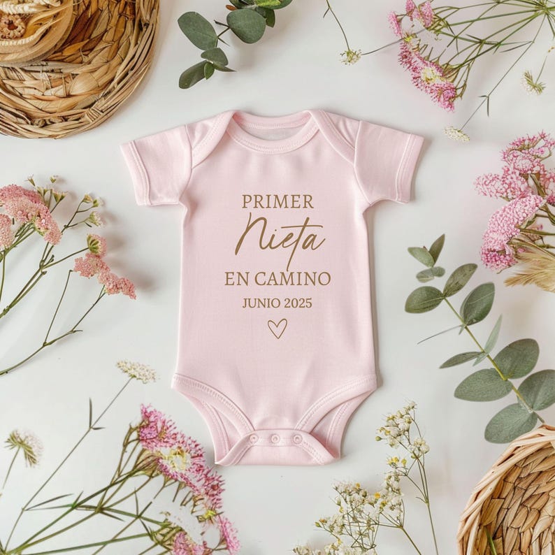 May include: Pink baby onesie with the text "PRIMER NIETA EN CAMINO JUNIO 2025" and a small heart.