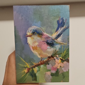 以下が含まれることがあります： 長方形のパネルに描かれた油絵で、枝にとまった小さな鳥が表現されています。鳥はピンク、青、白の柔らかな筆致で描かれています。背景は落ち着いた緑と紫の色調で、絵具の質感がはっきりと見て取れます。