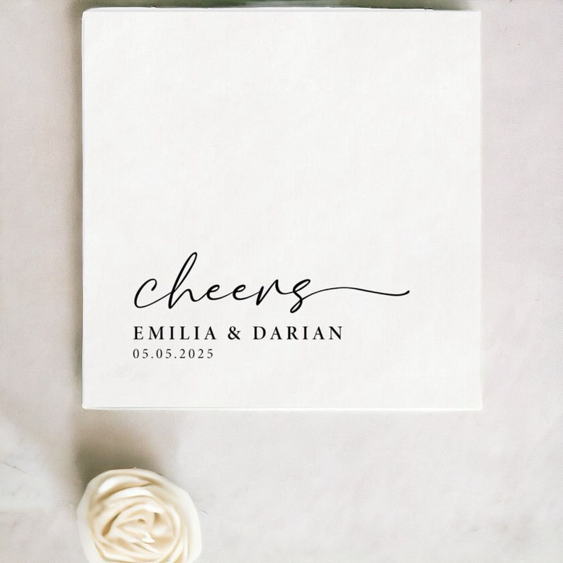 Pode incluir: Cart&atilde;o branco com a palavra "cheers" escrita em it&aacute;lico. Abaixo da palavra "cheers" est&aacute; o texto "EMILIA & DARIAN" e a data "05.05.2025".