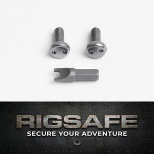 May include: Two silver-colored metal security screws with two small circular holes on the head, accompanied by a matching specialized metal driver bit with a U-shaped tip. Below, the text RIGSAFE SECURE YOUR ADVENTURE is displayed.