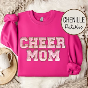 Puede incluir: Sudadera rosa con un parche de chenilla dorado y rosa que dice "CHEER MOM".