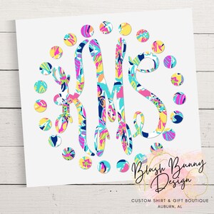 May include: A white print featuring a monogram with the letters K, M, and S in a colorful floral pattern. The monogram is surrounded by colorful polka dots. The design includes the text "Blush Bunny Design" and "CUSTOM SHIRT & GIFT BOUTIQUE AUBURN, AL".