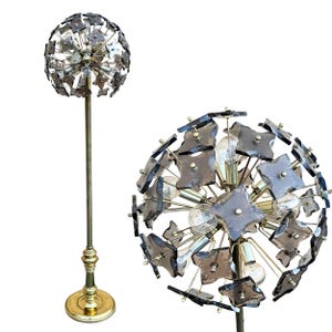 May include: A vintage floor lamp with a spherical shade composed of gray, star-shaped glass pieces. The lamp has a brass base and stem, and the light bulbs are visible within the shade. The lamp is a unique piece of home decor.