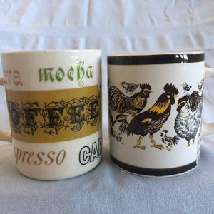 May include: Two ceramic coffee mugs. One mug has a brown, black, and yellow rooster design. The other mug has a gold and brown stripe with the word "coffee" in black lettering.