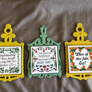 May include: Three decorative trivets with ceramic tiles and ornate frames. One is yellow with the text "Singlehandedly I have fought my way into this Hopeless Moss." Another is green with "Lord, grant me PATIENCE but I want it RIGHT NOW!" The third is yellow with "When all else fails, Eat!"