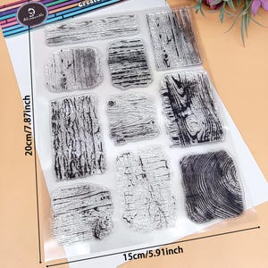 May include: Clear stamps with various wood grain patterns. The stamps are arranged on a clear sheet, with dimensions of 15cm/5.91 inches wide and 20cm/7.87 inches tall. The stamps are ideal for crafting and scrapbooking projects.