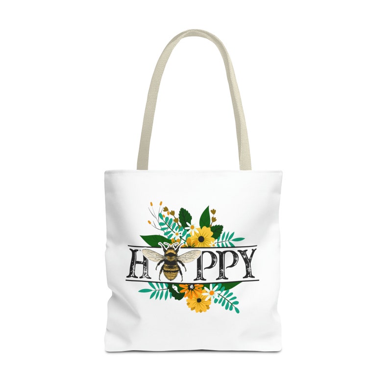 May include: A white tote bag with a bee and floral design. The text "HAPPY" is written in black with a vintage style font.