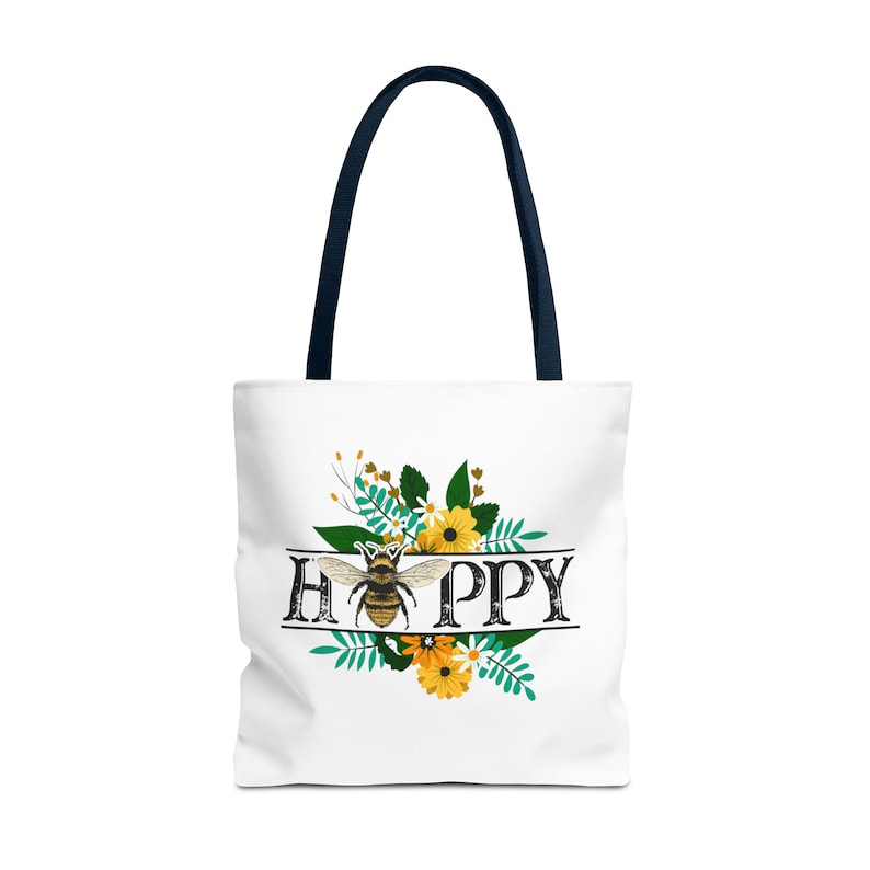 May include: White tote bag with a navy blue handle. The bag features a floral design with a bee in the center and the word "HAPPY" written in a vintage font.