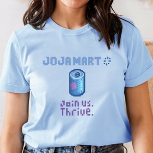 May include: Light blue t-shirt with a pixelated image of a can of Joja Cola and the text "JOJA MART" with a loading symbol and "Join us. Thrive."
