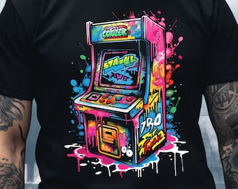 May include: A black t-shirt with a colorful graphic of an arcade game. The game is painted in a graffiti style with bright colors and drips. The game's screen says "STAY ALL NIGHT".