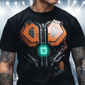 May include: Black t-shirt with a graphic print of a futuristic, mechanical chest piece. The chest piece is made of orange and gray metal and has a glowing green light in the center.