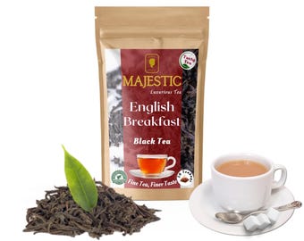 May include: A brown paper bag with a red and gold label that says "Majestic Luxurious Tea English Breakfast Black Tea Fine Tea, Finer Taste". The bag is filled with black tea leaves. A cup of tea and a saucer with sugar cubes and a spoon are in the lower right corner of the image.