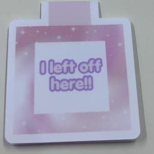 May include: A sticker in the shape of a perfume bottle with a pink and white gradient background. The sticker has the text "I left off here!!" in purple letters.