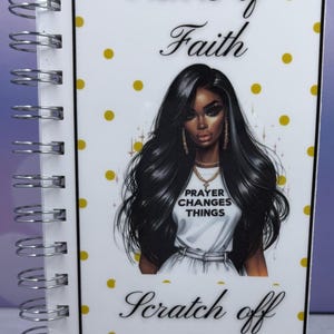 May include: A spiral-bound scratch-off book with the text "Sisters of Faith" and "Scratch off Book." The cover features an illustration of a woman with long black hair and the text "Prayer Changes Things."