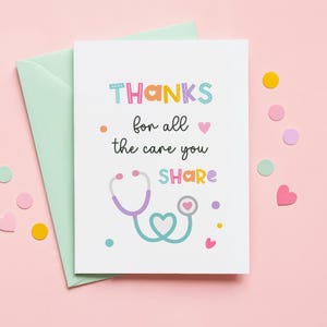 Puede incluir: Una tarjeta de felicitación blanca con un sobre verde claro que presenta el texto THANKS for all the care you SHARE en letras coloridas. Debajo del texto se ilustra un estetoscopio con una pieza torácica y tubo en forma de corazón, con corazones.
