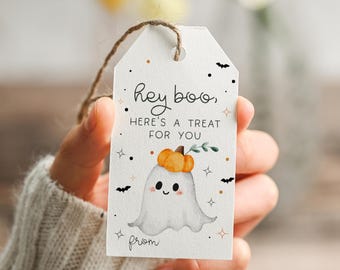 May include: White gift tag with a watercolor illustration of a friendly ghost wearing a pumpkin hat. The tag reads "Hey boo, here's a treat for you" with decorative stars, dots, and bats. A brown twine string is attached.
