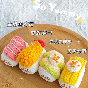 May include: Four crocheted sushi pieces on a wooden plate. The sushi includes pink, yellow, green, and white elements, resembling tuna, tempura shrimp, avocado, and egg. The text "So Yummy" is above the sushi.