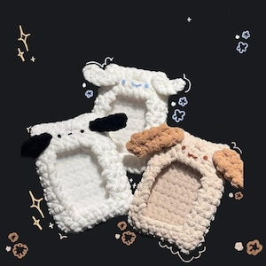 May include: Three handmade, fluffy phone cases shaped like cartoon sheep. One is white with black ears, another is white with blue accents, and the third is beige with brown ears. The cases have a soft, textured appearance.