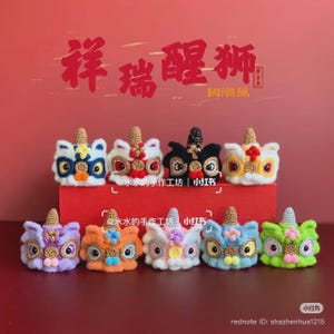 May include: A selection of colourful, handcrafted lion dance head ornaments. Each miniature lion head features intricate crochet details, including a textured mane, expressive eyes, and a decorative horn. The ornaments are displayed on a red surface against a red background.