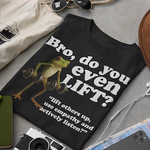 May include: Black t-shirt featuring a cartoon frog lifting weights, with the text "Bro, do you even LIFT?" and the quote "lift others up, use empathy and actively listen?"