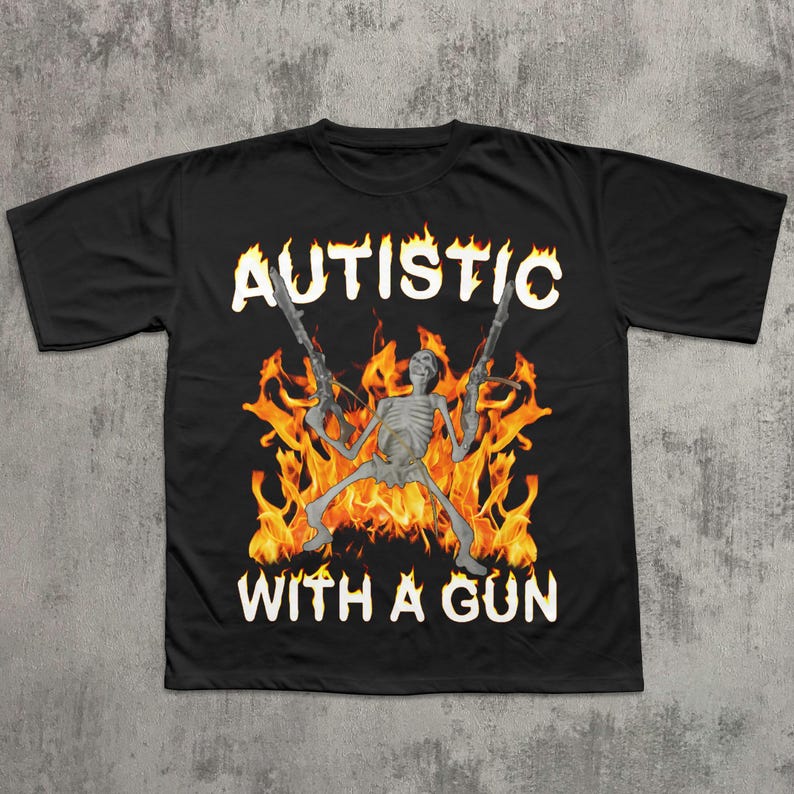 May include: Black t-shirt featuring a skeleton holding two guns, surrounded by flames. The words "AUTISTIC" and "WITH A GUN" are printed in white. The design is centered on the shirt.