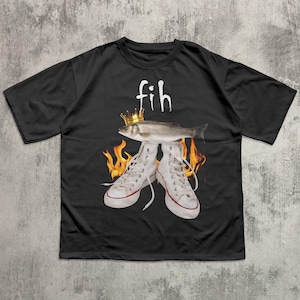 May include: Black t-shirt with a graphic design featuring a fish wearing a crown above a pair of white sneakers. The word "fih" is above the fish. Flames are behind the sneakers.