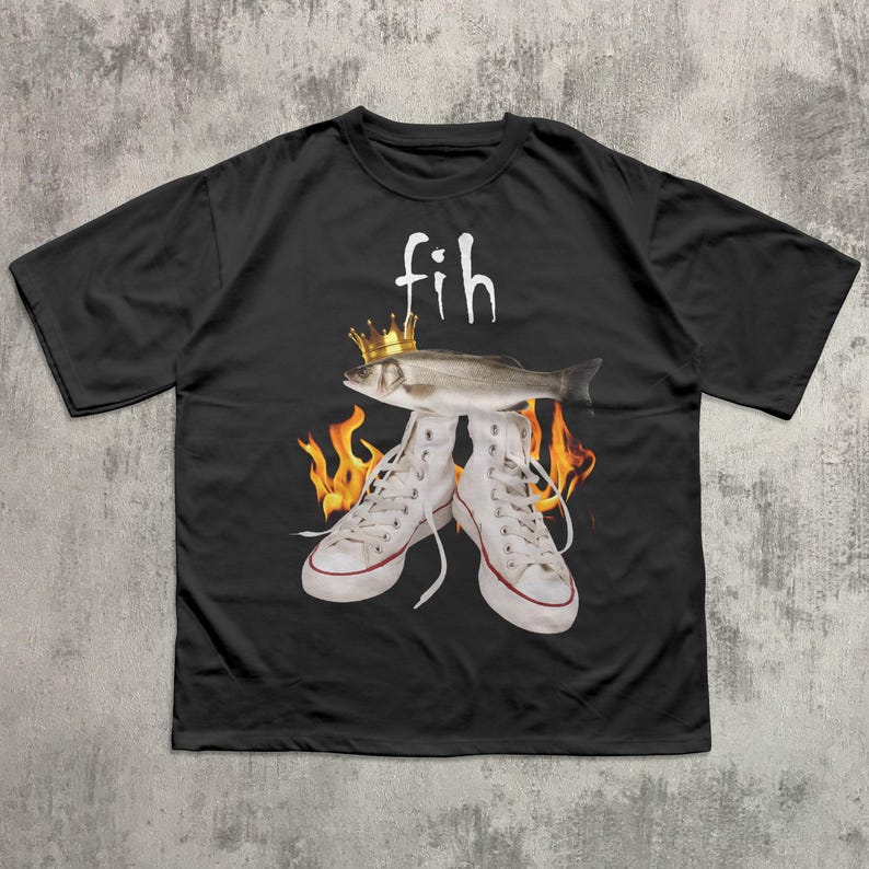 May include: Black t-shirt with a graphic design featuring a fish wearing a crown above a pair of white sneakers. The word "fih" is above the fish. Flames are behind the sneakers.