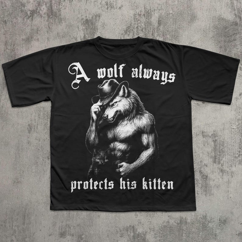 May include: Black t-shirt featuring a detailed illustration of a wolf wearing a hat, with the text "A wolf always protects his kitten" in white gothic lettering. The wolf is depicted with a muscular physique.