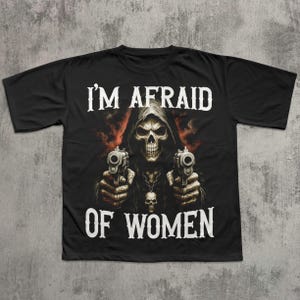 May include: Black t-shirt featuring a grim reaper graphic holding two pistols. The text "I'M AFRAID OF WOMEN" is printed in white above and below the image. The design has a dark, edgy aesthetic.