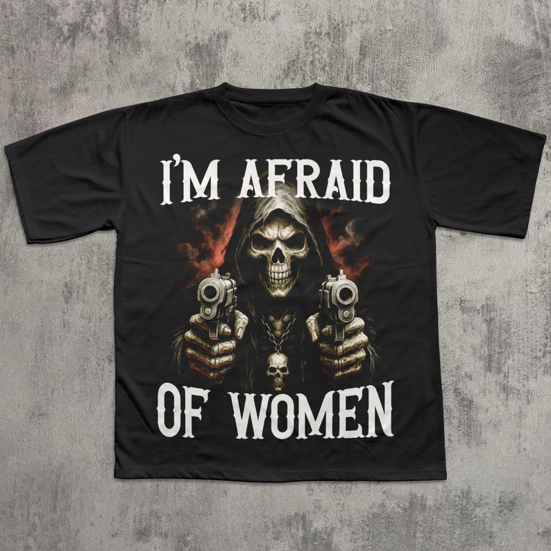 May include: Black t-shirt featuring a grim reaper graphic holding two pistols. The text "I'M AFRAID OF WOMEN" is printed in white above and below the image. The design has a dark, edgy aesthetic.