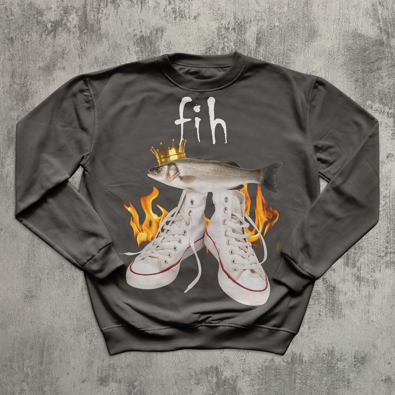 May include: Dark grey sweatshirt featuring a fish wearing a gold crown, standing on white high-top trainers. The word "fih" is above the fish in white, with flames around the trainers.