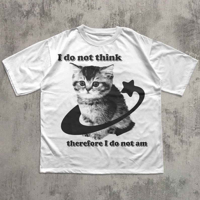 May include: White t-shirt featuring a black and white graphic of a kitten encircled by a crescent and star. The text "I do not think" is above the kitten, and "therefore I do not am" is below.