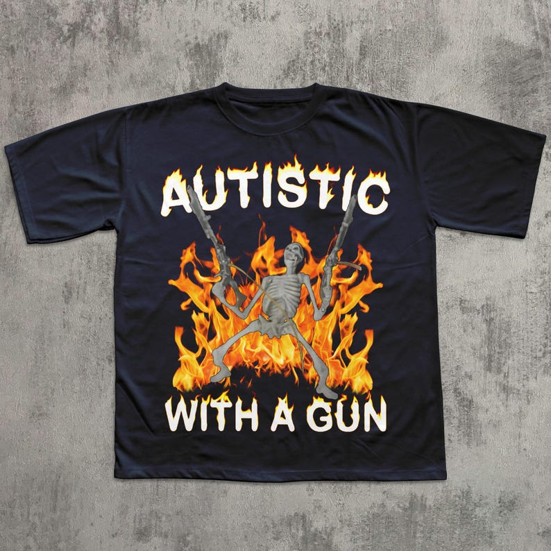 May include: Black t-shirt featuring a skeleton holding two guns, set against a backdrop of flames. The text "AUTISTIC" is arched above the skeleton, with "WITH A GUN" below, all in white lettering. The shirt has a crew neck and short sleeves.