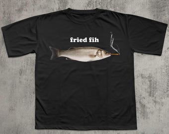 May include: Black t-shirt featuring a fish with a cigarette and the text "fried fih" in white. The fish is a realistic illustration with detailed scales and fins. The cigarette is lit, with smoke rising.