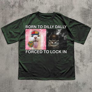 May include: Dark green t-shirt with the text "BORN TO DILLY DALLY FORCED TO LOCK IN". The shirt features two images of cats, one with a lollipop and the other wearing a helmet.