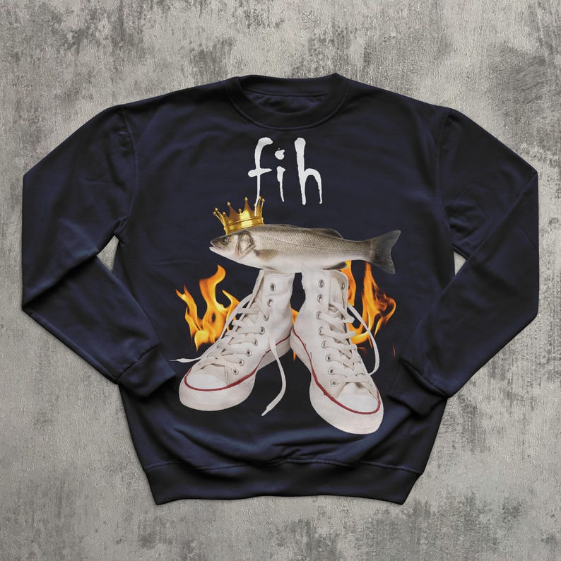 May include: Navy blue sweatshirt with a graphic design. It features a fish wearing a gold crown above white high-top trainers. The word "fih" is written above the fish in white. Flames are visible behind the trainers.