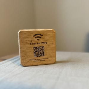 Könnte beinhalten: Ein Holzschild mit einem QR-Code und dem Text "Scan for WIFI". Der Text unter dem QR-Code lautet "Netzwerk: HolzmoechibyStefan Passwort: Heizliebe".