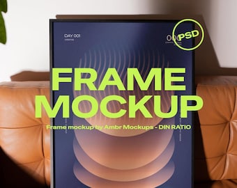 May include: A black framed poster mockup with a dark blue and orange abstract design. The words "FRAME MOCKUP" are in large, bright green letters. The image also includes the text "Frame mockup by Ambr Mockups - DIN RATIO" and the Photoshop and Photopea logos.