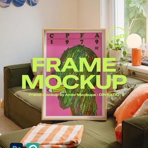 Op de afbeelding: Een ingelijste poster met een roze achtergrond en groene en zwarte kunstwerken staat tegen een groene bank. De poster heeft de tekst "FRAME MOCKUP" in grote, neon groene letters. Een oranje en wit gestreepte deken is opgevouwen op de bank.