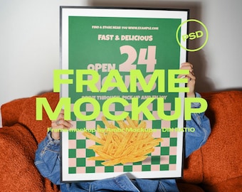 May include: A framed poster mockup featuring a green and pink checkered design with a graphic of french fries. The poster includes the text "FAST & DELICIOUS" and "OPEN 24". The person holding the frame is wearing a denim jacket.