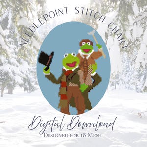 Könnte beinhalten: Ein digitales Needlepoint-Stichdiagramm für 18 Mesh-Gewebe mit einer verpixelten Illustration zweier grüner Froschfiguren in Winterkleidung. Ein Frosch hält einen schwarzen Zylinder, der andere einen Gehstock vor einem hellblauen ovalen Hintergrund.