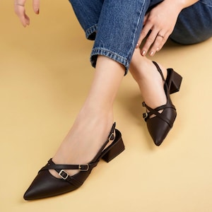 Peut inclure: Chaussures à talons slingback en cuir marron avec des brides croisées et des boucles dorées.